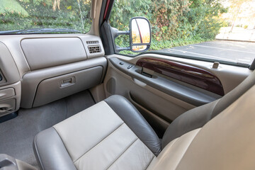 Front passenger beige leather seats, interior of an older 2004 American 4x4 family suv truck. Door window power switches, highlighting clean and well-preserved cabin details, speakers, armrests 