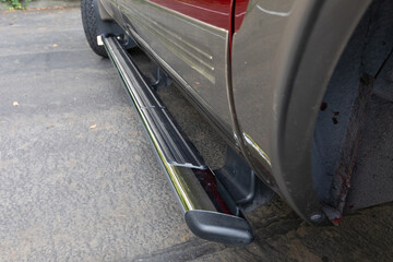 Side step chrome running board detail on a 2004 American 4x4 family SUV showing rugged exterior design and textured surface for easy access, captured outdoors on clean pavement © Hrach