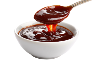 Close-up shot of a white bowl filled with glossy, rich brown sauce and a spoon holding more