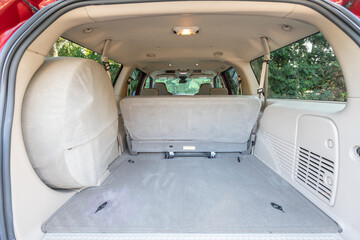 Trunk, spare tire, rear two row beige leather bench seats, interior of an older 2004 American 4x4 family suv truck. Shown in natural daylight, highlighting clean and well-preserved cabin details  