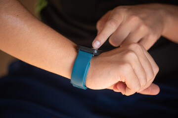 Person interacting with smartwatch on wrist while sitting outdoors