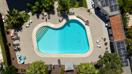 Aerial zenithal view of an empty swimming pool in the garden of a villa.
