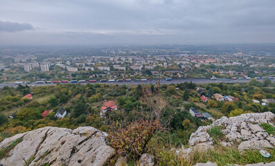Scenic overlook of Tatabánya, Hungary, from the limestone cliffs of Szédítő Rock, with the highway and city blocks stretching into the mist.