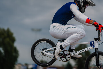 Fototapeta premium Valmiera, Latvia - July 12, 2025: BMX rider performing mid-air stunt on Commencal bike during competitive race event. BMX European championships