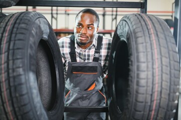 Professional African american worker with tire. Man is in the tire fitting car service