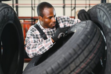 Professional African american worker with tire. Man is in the tire fitting car service