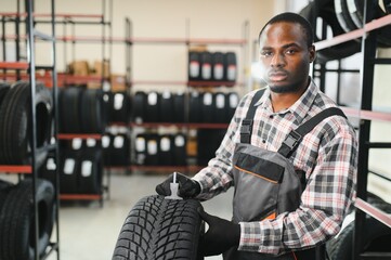 A professional African american worker in a car service measures the tread diameter of a wheel with...