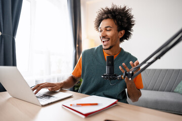 Happy African American man podcaster typing on keyboard using microphone, typing on keyboard