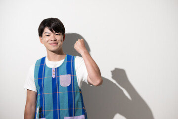エプロンを着てガッツポーズをする男性　保育士・介護士などのイメージ