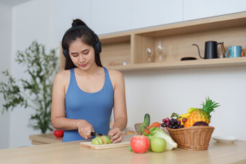 Wellness. Enjoying healthy cooking with headphones in modern kitchen.