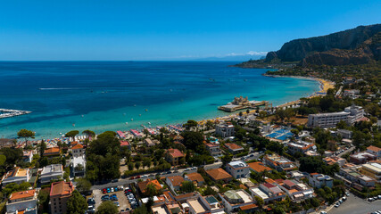 Aerial view of houses, apartments, and buildings among the trees in Mondello, Palermo, Italy. The Mediterranean Sea is on the horizon.