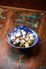Green and kalamata olives and feta cheese on rustic wooden background. Soft focus.	