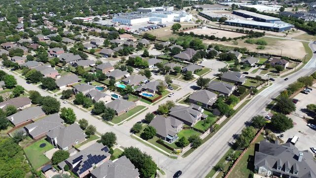 Suburban grid layout in North Richland Hills, Texas, showing rows of two-story homes with green lawns, backyard pools. Background reveals light industrial buildings, logistic hubs warehousing