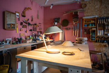 Handcrafted wooden lamp with unique design connected by wire on table in carpenter workshop for...
