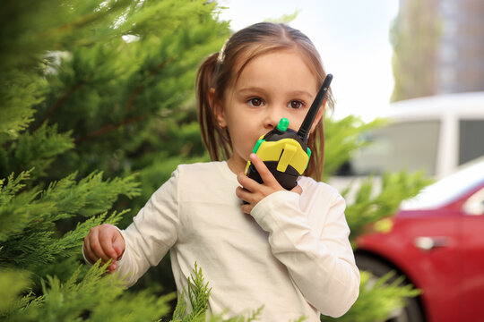 Little girl playing with walkie talkie toy outdoors