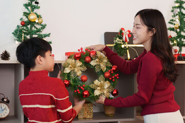 SSTK Christmas: Smiling woman and child arranging festive wreath for holiday decor