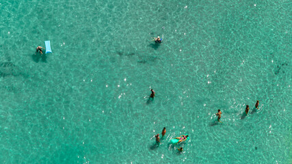 Aerial view of people bathing in the azure sea. The water is calm and clean.