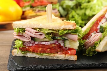Tasty sandwiches with ham and vegetables on wooden table, closeup