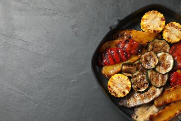 Delicious grilled vegetables in pan on dark textured table, top view. Space for text