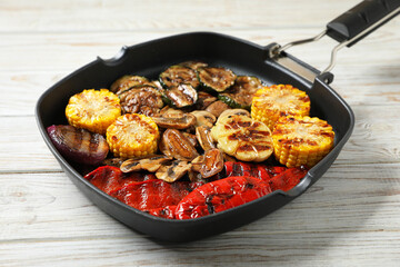 Delicious grilled vegetables and mushrooms in pan on light wooden table, closeup