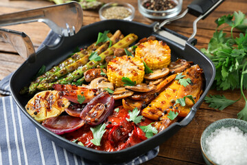 Delicious grilled vegetables, mushrooms and spices in pan on wooden table, closeup