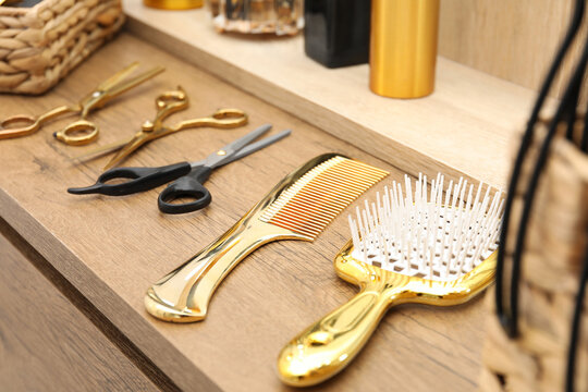 Different hair styling tools on wooden vanity in salon, closeup