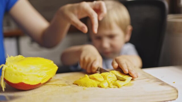 Crying boy cutting a ripe mango with a knife
