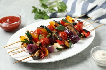 Skewers with tasty grilled vegetables and sauces on light grey marble table, closeup