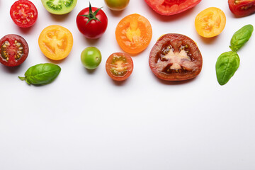 Ripe colorful tomatoes and basil on white background, flat lay. Space for text