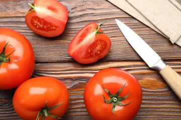 Fresh ripe tomatoes and knife on wooden table, flat lay