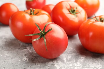 Fresh ripe tomatoes on grey textured table, closeup