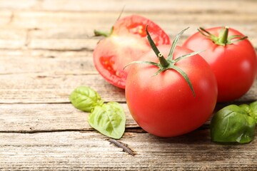 Fresh ripe tomatoes and basil on wooden table, closeup. Space for text