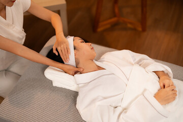 Asian adult woman receives professional neck head massage treatment for deep relaxation and stress relief in a serene spa setting
