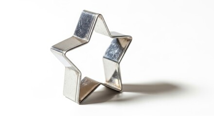 Fototapeta premium Metallic star cookie cutter on a white background, casting a distinct shadow.