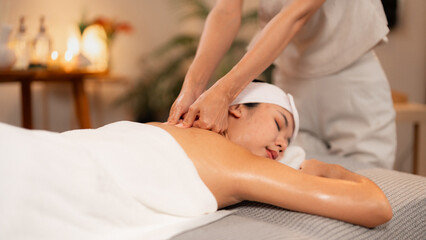 Adult Asian woman enjoys therapeutic back shoulder massage in serene luxury spa for relaxation
