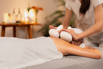 Asian woman receives authentic herbal compress spa massage professional therapist delivers soothing...