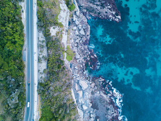 Aerial top-down view of coastal road, cliffs, and turquoise ocean in New South Wales, Australia