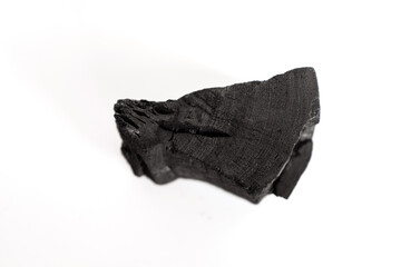 natural charcoal piece isolated on white background, showing rough porous texture and matte black surface, ideal for design projects about energy, fuel, art materials, or organic texture