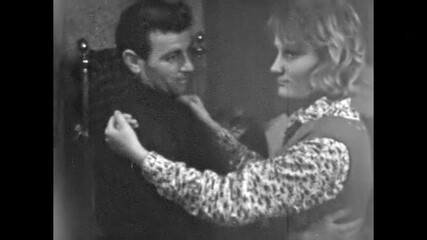 Young couple whirl in slow dance across room, man and woman close, romantic embrace showing love, playful motion and happy laughter, together joy. Old film. Archival retro 1960s. Vintage archive.