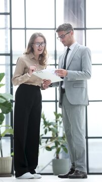 Two people are standing in front of a window