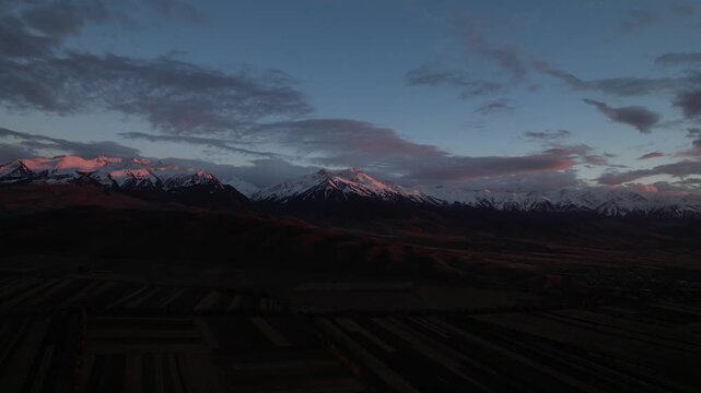 A Serene Dusk Over Majestic Snow-Capped Mountains, With Soft Pink and Purple Hues Illuminating the Sky and Reflecting on the Snowy Peaks, Capturing Nature's Tranquility.