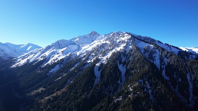 Majestic Snow-Capped Mountains Under Clear Blue Sky Showcasing the Beauty of Nature's Landscape with Lush Greenery and Jagged Peaks in a Serene Environment