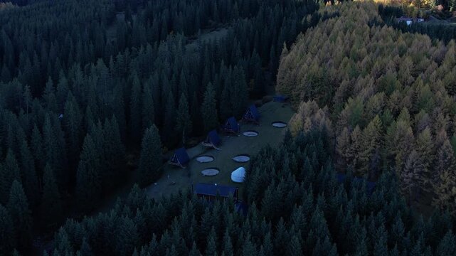Aerial View of Rustic Cabins Nestled Among Lush Green Forests Surrounded by Dense Trees and Autumn Foliage in a Picturesque Natural Setting