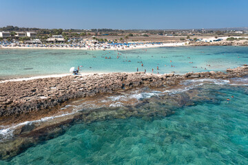 Tourists are enjoying a sunny summer day swimming and sunbathing at the Ayia Thekla beach. Ayia Napa, Cyprus