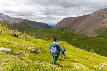 Obraz premium A group of active hikers descending a green grassy valley