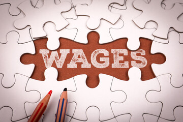 Word wages written on brown background under white puzzle pieces symbolizing salary income payment and employment concept