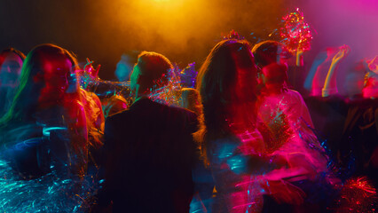 Dancing crowd enjoying Christmas celebration in vibrant colorful blur. Concept of nightlife advertising, emotional expression, youth visuals, and club culture