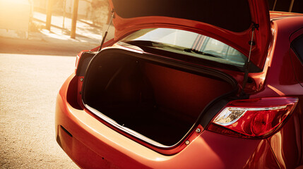 compact car, trunk open, low rear side angle, vertical format, sunny outdoor lighting, commercial photography.