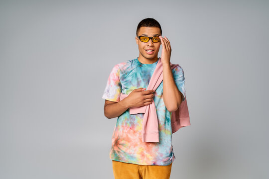 Vibrant young man expressing joy while wearing colorful attire and stylish sunglasses