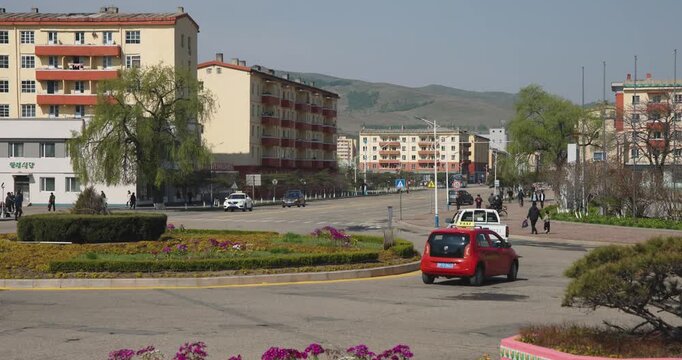 May 8, 2025 - Rason, North Korea - A street in a North Korean border town. Cars and people are moving along a deserted street.